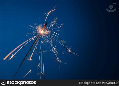 Bright burning sparkler bengal fire on blue background