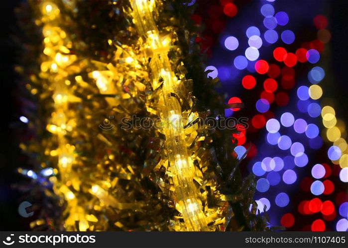 Bright Christmas decoration, colorful lights of bulbs, garlands and shiny tinsel, abstract background out of focus