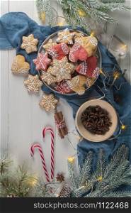 Bright Christmas or New Year wooden background with fir branches, Christmas decorations, Christmas gingerbread cookies, Christmas sweets. Copy space. View from above