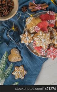 Bright Christmas or New Year wooden background with fir branches, Christmas decorations, Christmas gingerbread cookies, Christmas sweets. Copy space. View from above