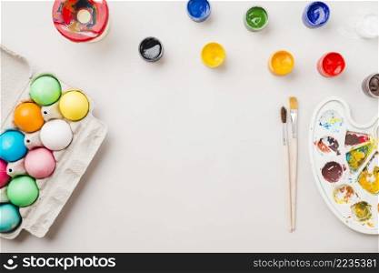 bright collection colored eggs near container near brushes water colors palette
