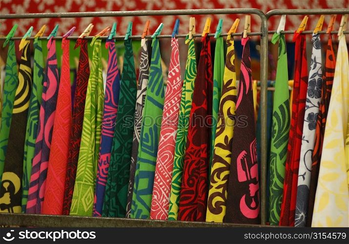 Bright colored fabrics hung from a rack at the straw market, Papeete, Tahiti