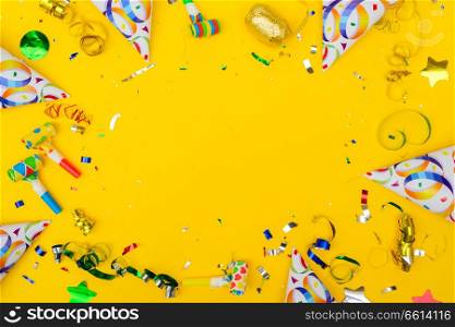 Bright colorful carnival or party frame of confetti on yellow table frame. Flat lay style, birthday or party greeting card with copy space.. Bright colorful carnival or party scene
