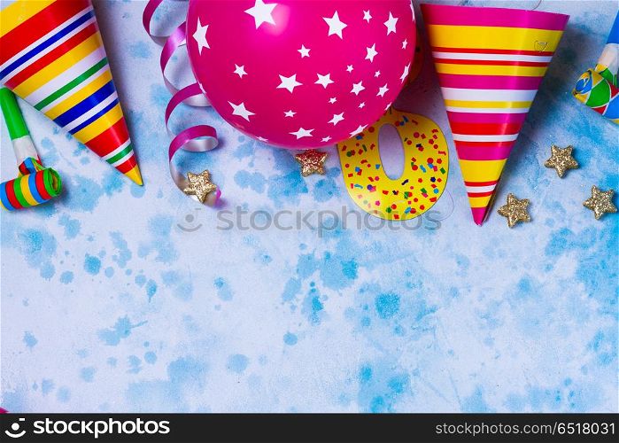 Bright colorful carnival or party scene. Bright colorful carnival or party border of balloons, streamers and confetti on blue table. Flat lay style, birthday or party greeting card with copy space.