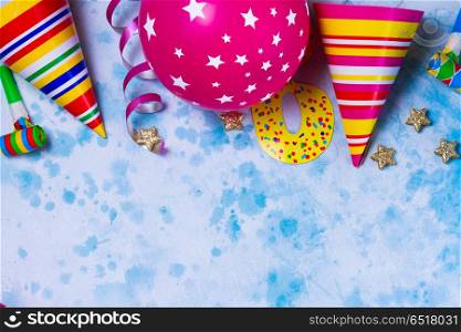 Bright colorful carnival or party scene. Bright colorful carnival or party border of balloons, streamers and confetti on blue table. Flat lay style, birthday or party greeting card with copy space.