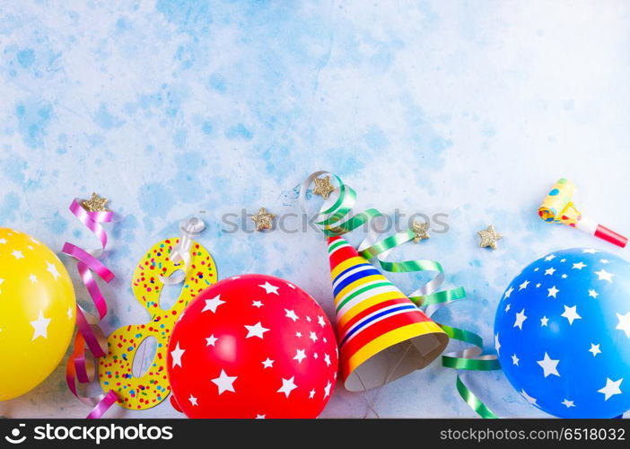 Bright colorful carnival or party scene. Bright colorful carnival or party border of balloons, streamers and confetti on blue table background. Flat lay style, birthday or party greeting card with copy space.