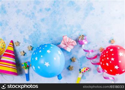 Bright colorful carnival or party scene. Bright colorful carnival or party border of balloons, streamers and confetti on blue table background. Flat lay style, birthday or festive party greeting card with copy space.