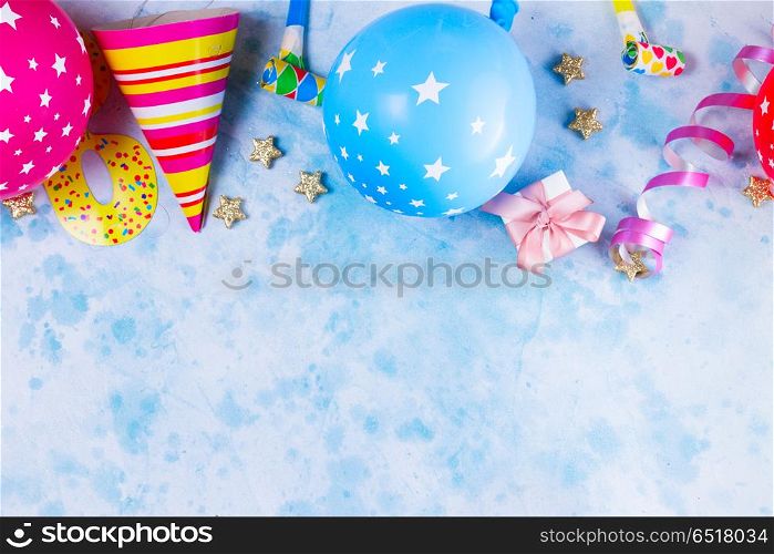 Bright colorful carnival or party scene. Bright colorful carnival or party border of balloons, streamers and confetti on blue. Flat lay style, birthday or party greeting card with copy space.