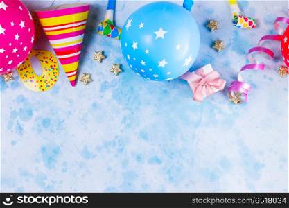 Bright colorful carnival or party scene. Bright colorful carnival or party border of balloons, streamers and confetti on blue. Flat lay style, birthday or party greeting card with copy space.