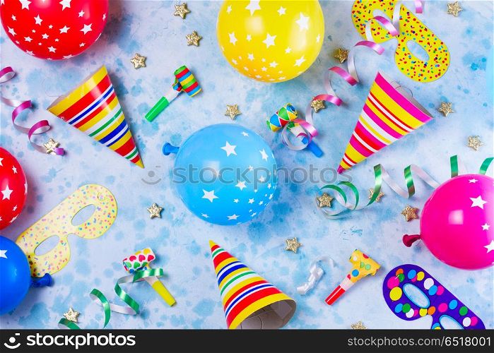 Bright colorful carnival or party scene. Bright colorful carnival or party pattern of balloons, streamers and confetti on blue table. Flat lay style, birthday or party greeting card.