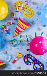 Bright colorful carnival or party scene. Bright colorful carnival or party pattern of balloons, streamers and confetti on blue table. Flat lay style, birthday or carnival party greeting card.