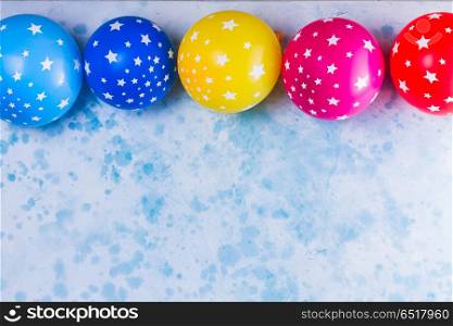 Bright colorful carnival or party scene. Bright colorful carnival or party scene frame of balloons on blue table. Flat lay style, birthday or party border with copy space.