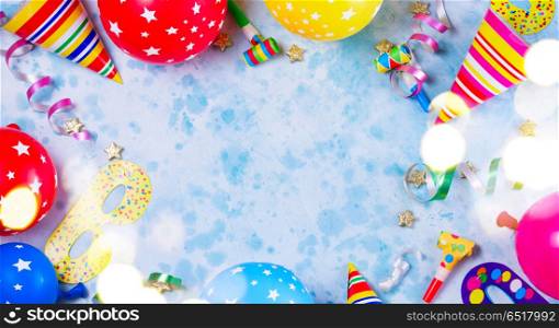Bright colorful carnival or party scene. Bright colorful carnival or party scene frame of balloons, streamers and confetti on blue table. Flat lay style, birthday or party greeting card with copy space and bokeh lights