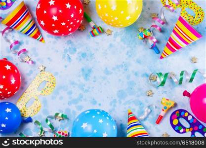 Bright colorful carnival or party scene. Bright colorful carnival or party scene frame of balloons, streamers and confetti on blue table. Flat lay style, birthday or party greeting card with copy space.