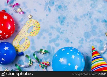 Bright colorful carnival or party scene. Bright colorful carnival or party scene frame of balloons, streamers and confetti on blue table. Flat lay style border, birthday or party greeting card with copy space.