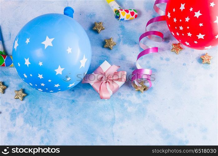 Bright colorful carnival or party scene. Bright colorful carnival or party scene of balloons, streamers and confetti on blue table. Flat lay style, birthday or carnival party greeting card with copy space.