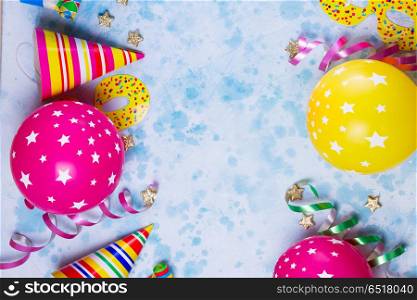 Bright colorful carnival or party scene. Bright colorful carnival or party scene of balloons, streamers and confetti on blue table background. Flat lay style, birthday or carnival party greeting card with copy space.