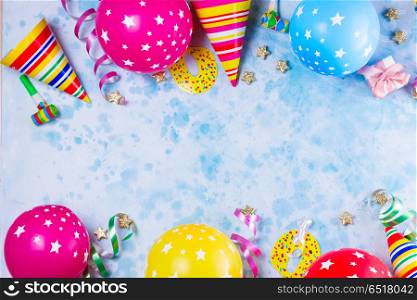 Bright colorful carnival or party scene. Bright colorful carnival or party scene of balloons, streamers and confetti on blue table. Flat lay style, birthday or party greeting card with copy space.