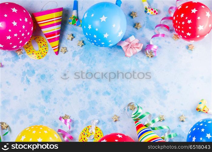 Bright colorful carnival or party scene. Bright colorful carnival or party scene of balloons, streamers and confetti on blue table background. Flat lay style, birthday or party greeting card with copy space.