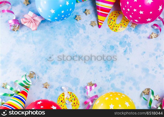 Bright colorful carnival or party scene. Bright colorful carnival or party scene of balloons, streamers and confetti on blue table background. Flat lay style, birthday or festive party greeting card with copy space.