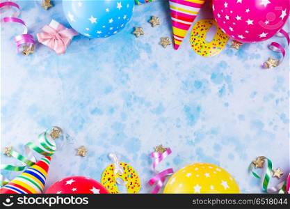 Bright colorful carnival or party scene. Bright colorful carnival or party scene of balloons, streamers and confetti on blue table background. Flat lay style, birthday or festive party greeting card with copy space.