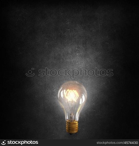 Bright electric bulb. Glowing glass light bulb on concrete background