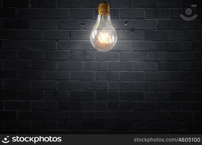 Bright electric bulb. Glowing glass light bulb on concrete background