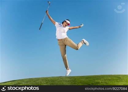 Bright excited brunette in sportswear jumping happily with golf driver in hands above green lawn on blue sky. . Cheerful woman jumping on golf course