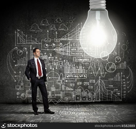 Bright idea. Businessman and light bulb with business sketches at background