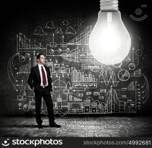 Bright idea. Businessman and light bulb with business sketches at background