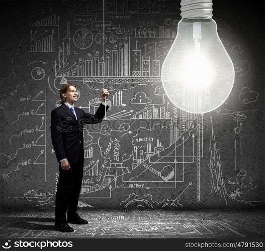 Bright idea. Businessman switching on light bulb with business sketches at background