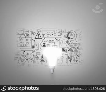 Bright idea for business growth. Glass glowing light bulb and business sketched ideas