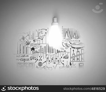 Bright idea for business growth. Glass glowing light bulb and business sketched ideas