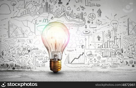 Bright idea for business growth. Glass glowing light bulb and business sketched ideas