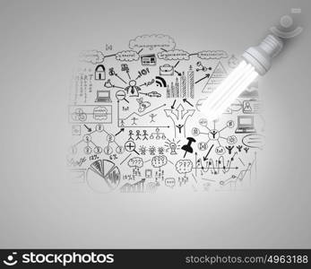 Bright idea for business growth. Glass glowing light bulb and business sketched ideas