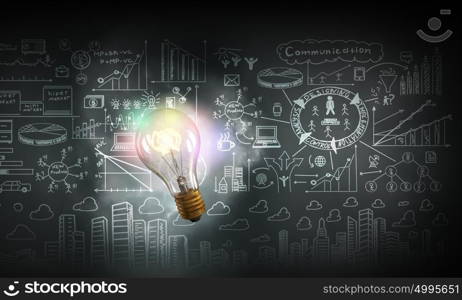 Bright idea for business growth. Glass glowing light bulb and business sketched ideas