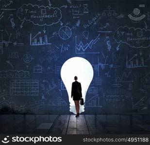 Bright idea for new success. Businesswoman in light of door in wall as idea concept