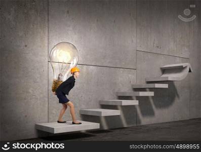 Bright idea for success achieving. Young engineer woman carrying glass light bulb on her back