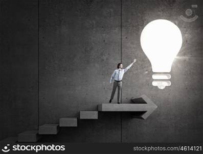 Bright idea for success. Businessman reaching hand to touch glass light bulb