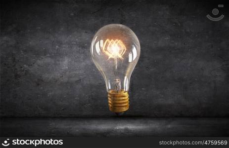 Bright idea for success. Glass glowing light bulb as idea sign on concrete background
