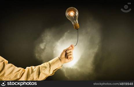 Bright idea in hand. Businessman hand holding glass glowing light bulb on dark background