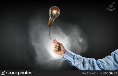 Bright idea in hand. Businessman hand holding glass glowing light bulb on dark background