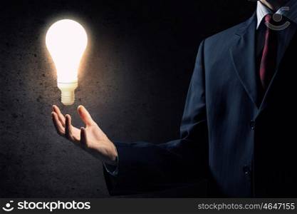 Bright idea in hand. Businessman with illuminated glass light bulb in hand