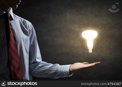 Bright idea in hand. Businessman with illuminated glass light bulb in hand