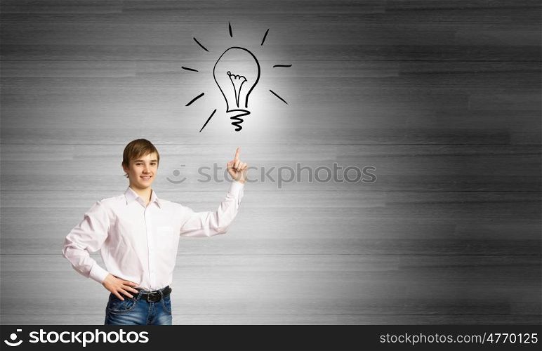 Bright idea. Smiling school boy pointing at light bulb with finger