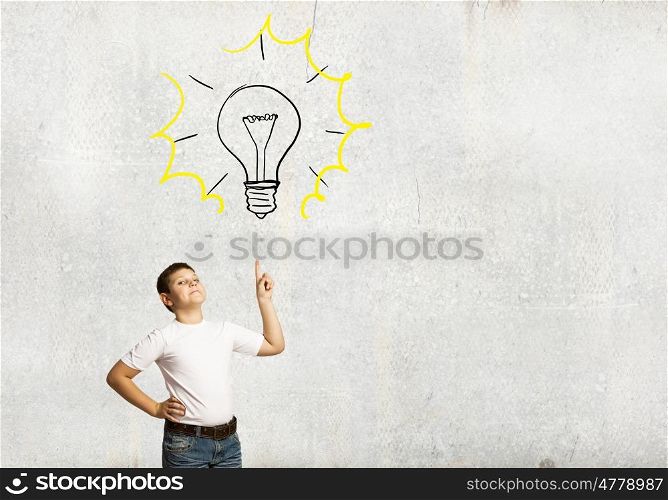 Bright idea. Smiling school boy pointing at light bulb with finger