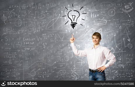 Bright idea. Smiling school boy pointing at light bulb with finger