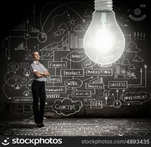 Bright idea. Young businesswoman with bulb and business sketches at background