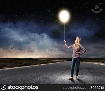 Bright idea. Young woman in casual holding bulb balloon