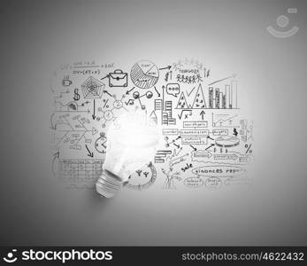 Bright ideas for business. Glowing light bulb on wall with sketches strategy plan